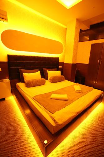 a bedroom with a large bed with yellow lights at Hotel OK in Prizren