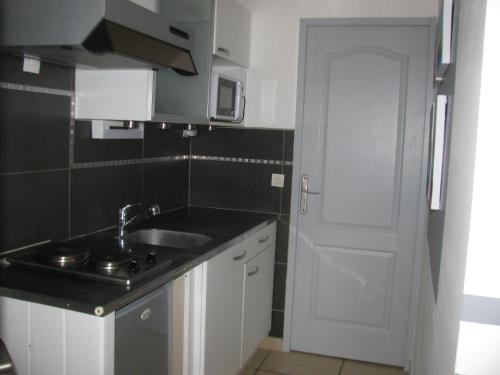 een kleine keuken met een wastafel en een witte deur bij Gite MARTIN in Grabels