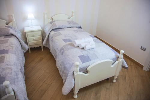 a bedroom with two beds and a table with a lamp at La Perla - Chic Accommodation in Sassari