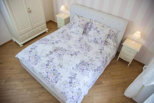 a bedroom with a bed with a floral bedspread and two tables at La Perla - Chic Accommodation in Sassari