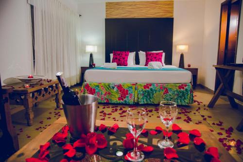 a bedroom with a bed with red flowers and wine glasses at Hotel San Antonio del Cerro in Pereira