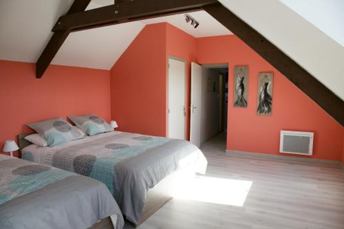 - une chambre mansardée avec des murs orange et un lit dans l'établissement La Petite Chesnee, à Sacey