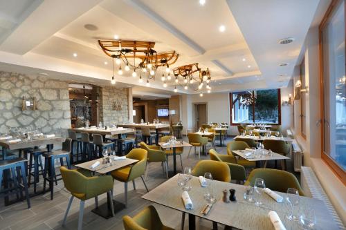 a restaurant with tables and chairs and a chandelier at La Mainaz Hôtel Restaurant Genève - Gex - Mijoux in Gex