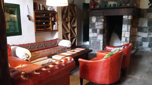 sala de estar con 2 sofás de cuero y chimenea en Estancia San Miguel, en Villa Yacanto