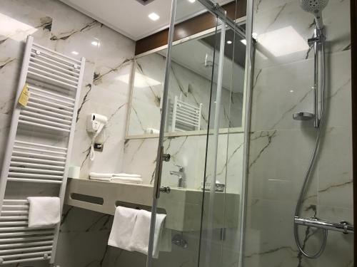 a bathroom with a shower and a sink and a mirror at KERCULLA Resort in Gjirokastër