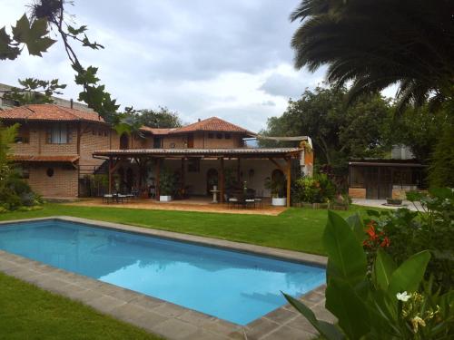 a house with a swimming pool in front of a yard at Rukka Lodge in Tumbaco