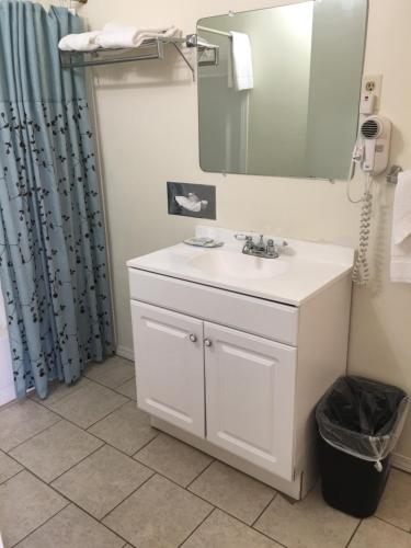 Un baño con un lavabo blanco y un espejo. en Travelers Inn Olney, en Olney