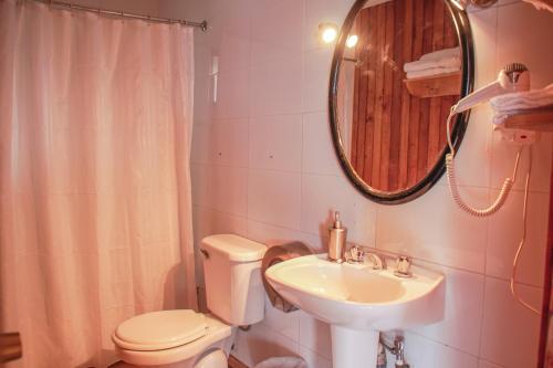 a bathroom with a sink and a toilet and a mirror at Cabañas Palafitos Los Pescadores in Castro