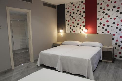 um quarto com uma cama branca e uma parede com bolinhas em Hotel Siskets em Torrente de Cinca