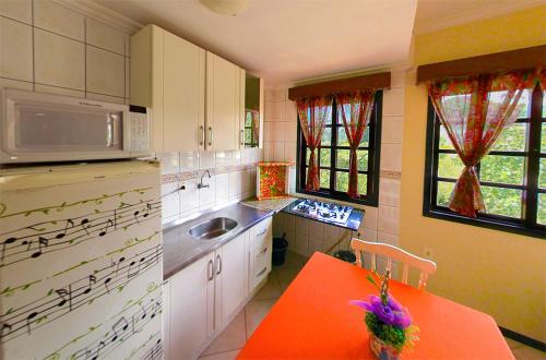 cocina con mesa roja y microondas en Pousada OceAnas Frente Mar Estaleiro en Balneario Camboriú