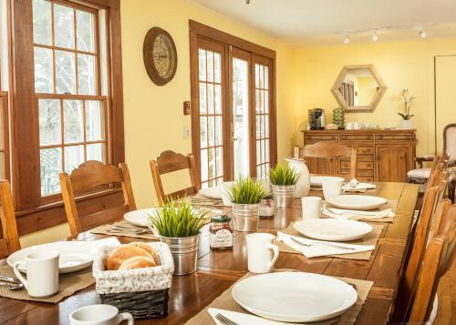 a dining room with a wooden table with white plates at Dragonfly Guest House in Ogunquit