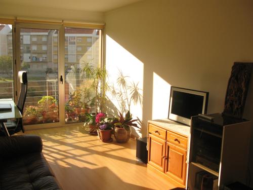 een woonkamer met een televisie en een glazen schuifdeur bij Apartment Lisbon Airport in Lissabon