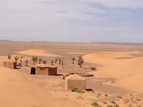 a desert with houses and palm trees in the distance at Maison Boutchrafine in Erfoud