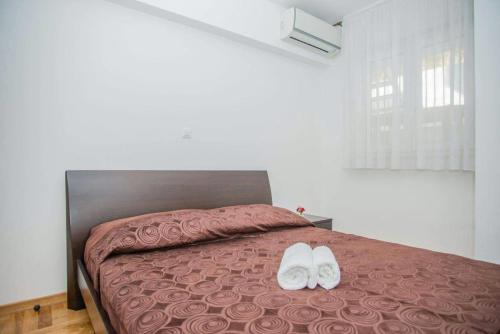dos zapatos blancos sentados en una cama en un dormitorio en Antonio Apartments on the beach, en Split