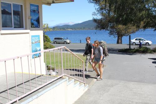 two people walking up the stairs of a building with a dog at Te Anau Lakefront Backpackers in Te Anau