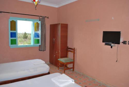 a bedroom with two beds and a tv and a chair at Gite Souss in Oulad Teima