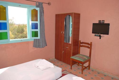 a bedroom with a bed and a chair and a television at Gite Souss in Oulad Teima