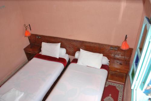 two beds in a room with two lamps on the wall at Gite Souss in Oulad Teima