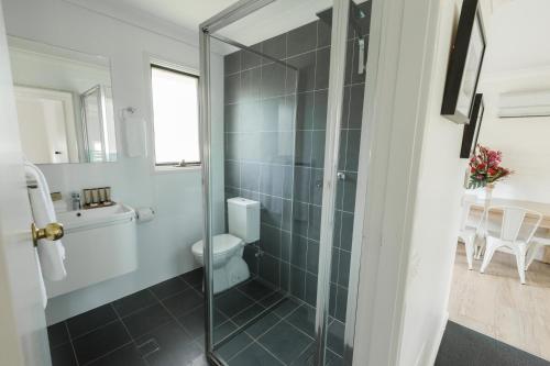 a bathroom with a toilet and a glass shower at Pokolbin Village Estate in Pokolbin