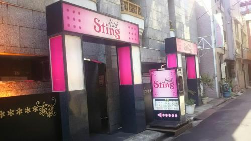 a building with pink and white signs on it at Hotel Sting in Tokyo