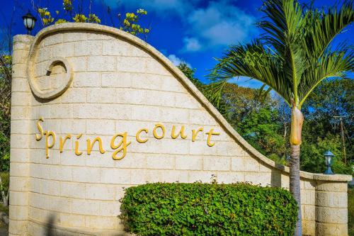 a sign for a spring court with a palm tree at 10 Springcourt Barbados in Bridgetown