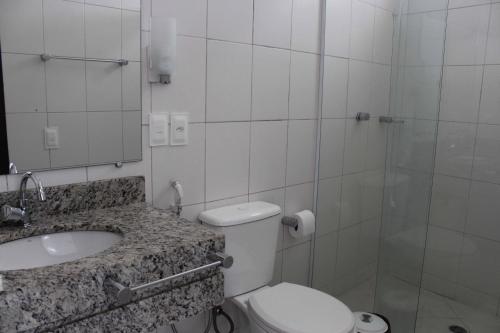 a bathroom with a toilet and a sink and a shower at Hotel Pousada da Néia in Cananéia
