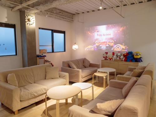 a living room with couches and tables at USJに一番近いゲストハウス J-Hoppers Osaka Universal in Osaka