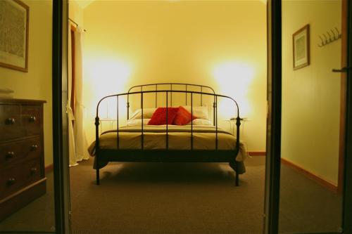 a bedroom with a bed with red pillows and a mirror at Butterworth Cottage in Castlemaine