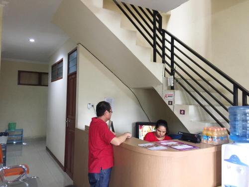 two people standing at a counter in a building at Wisma Mawas in Makassar