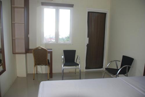 a room with chairs and a bed and a window at Avon's Residence in Manado