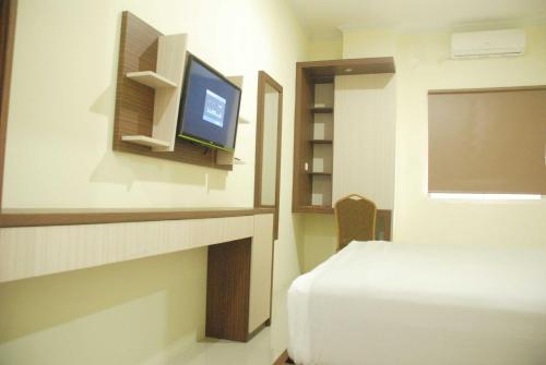 1 dormitorio con 1 cama y TV en una habitación en Avon's Residence, en Manado