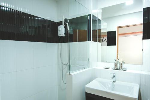 a white bathroom with a sink and a shower at deVloft hotel Korat in Nakhon Ratchasima