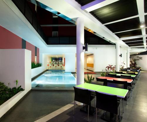 a pool with tables and chairs in a building at Amaris Hotel Cimanuk Bandung in Bandung