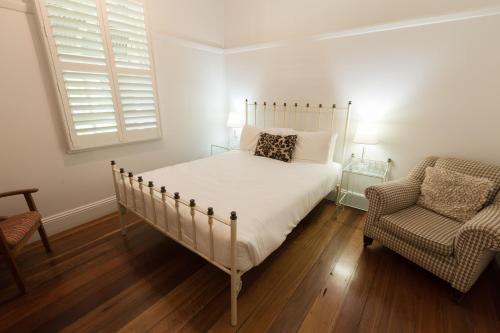 a bedroom with a bed and a chair and a window at Pooles Rock Vineyard Accommodation in Pokolbin