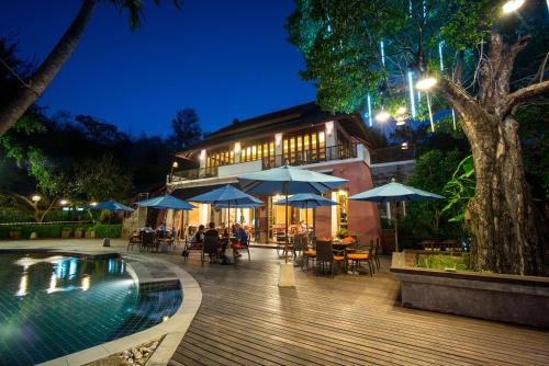 a resort with a pool and tables and umbrellas at Sibsan Resort & Spa Maetaeng SHA in Mae Taeng