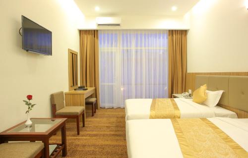 a hotel room with two beds and a television at Red Palace Hotel in Da Nang