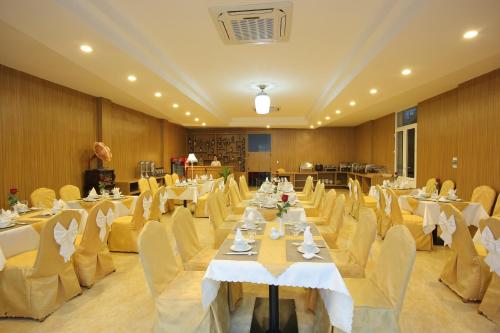 un salón de banquetes con mesas blancas y sillas amarillas en Red Palace Hotel, en Da Nang