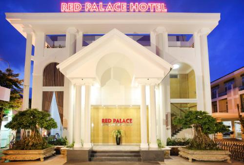 a red palace hotel with two trees in front of it at Red Palace Hotel in Da Nang