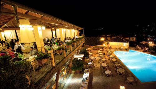 un grupo de personas sentadas alrededor de una piscina por la noche en Hotel Barbieri, en Altomonte