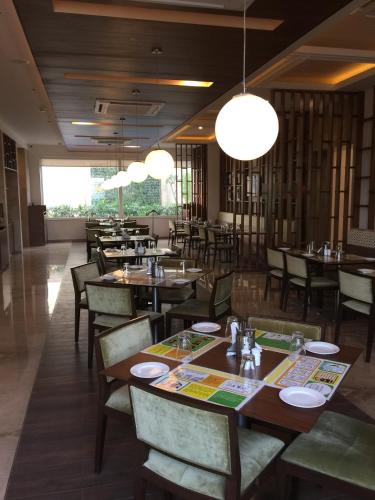 een restaurant met houten tafels, stoelen en verlichting bij Lemon Tree Hotel, Sector 60, Gurugram in Gurgaon