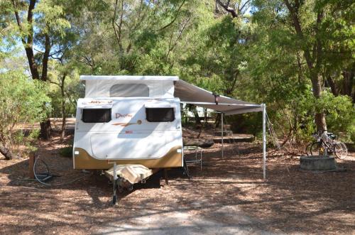 a rv parked under a tent in the woods at Coalmine Beach Holiday Park in Walpole