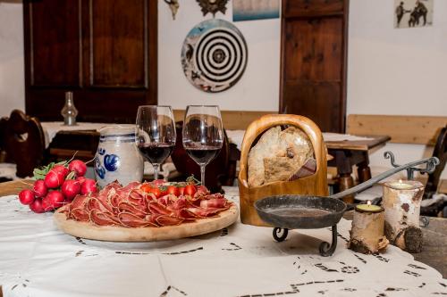 a table with a pizza and two glasses of wine at Hotel Alexandres in Appiano sulla Strada del Vino