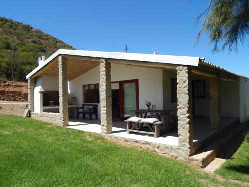 a small white house with a picnic table in front of it at Sipreslaan Selfsorg Gastehuis in Ladismith