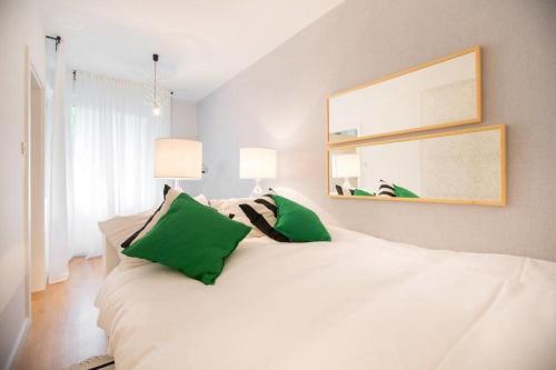 uma cama branca com almofadas verdes num quarto em Hella Apartment em Zagreb