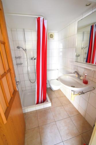 a bathroom with a red and white shower curtain at The River Holiday Apartment in Interlaken