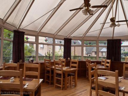a restaurant with wooden tables and chairs and a ceiling at The Crown Hotel in Peebles