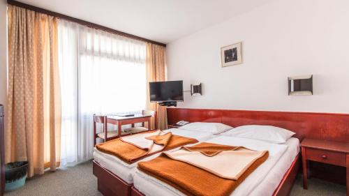 a bedroom with a large bed with a large window at Hotel Matija Gubec in Stubicke Toplice