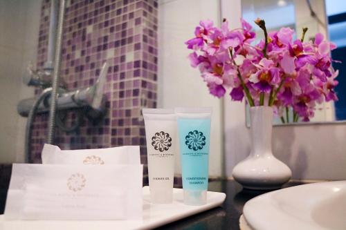 a table with two facial cleansers and a vase with flowers at CA Hotel and Residence Phuket - SHA Extra Plus in Phuket