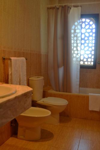 a bathroom with a toilet and a tub and a sink at Hotel Reyes Ziries in Albolote
