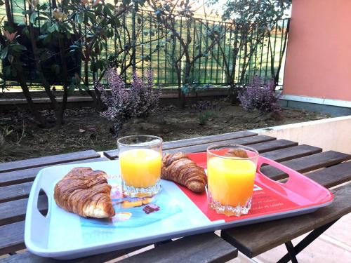 a tray with two glasses of orange juice and pastries on a table at Terrasses De Saint Martin - Très Calme et Agréable avec Grande Terrasse Ombragée - Résidence Privée - Idéalement située - Parking privatif possible in Montélimar